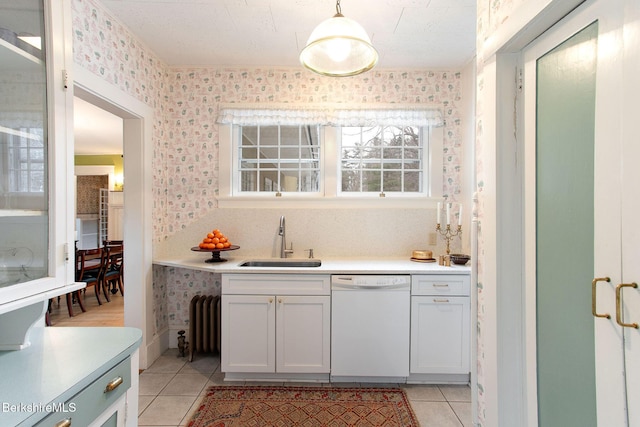 kitchen featuring a sink, light countertops, white dishwasher, and wallpapered walls