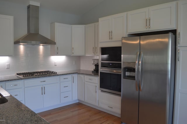 kitchen with white cabinets, stainless steel appliances, and wall chimney range hood