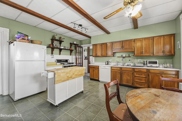 kitchen with beam ceiling, dark tile patterned flooring, brown cabinets, white appliances, and light countertops