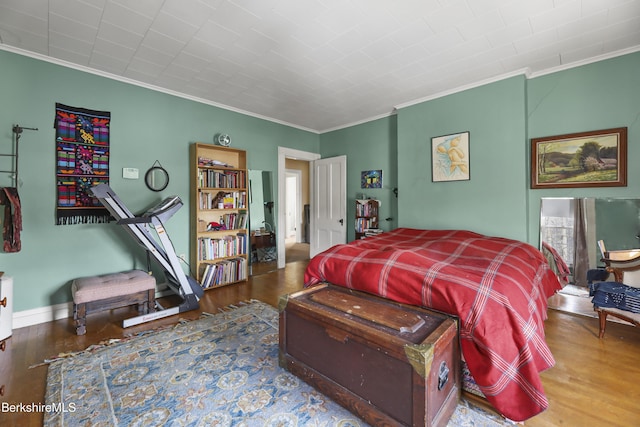 bedroom with crown molding, wood finished floors, and baseboards