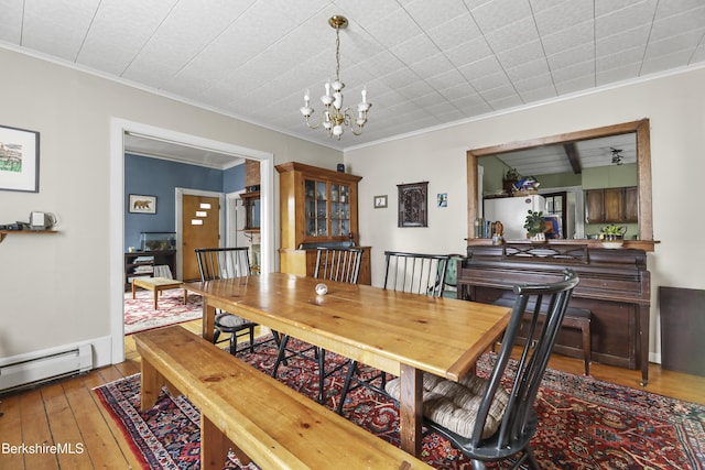 dining area featuring a baseboard heating unit, wood-type flooring, an inviting chandelier, and crown molding