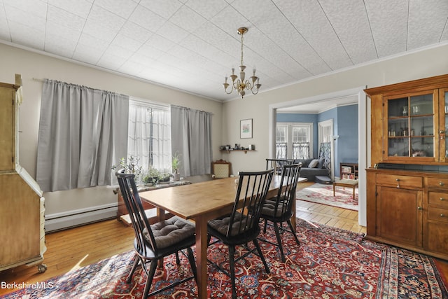 dining room with a notable chandelier, wood-type flooring, a healthy amount of sunlight, and baseboard heating