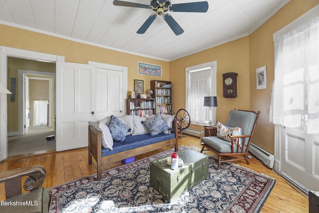 living room with ornamental molding, a baseboard heating unit, and wood-type flooring