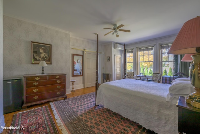 bedroom featuring crown molding, ceiling fan, light wood-type flooring, fridge, and a wall unit AC