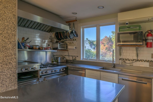 kitchen with decorative backsplash, stainless steel appliances, sink, wall chimney range hood, and an AC wall unit