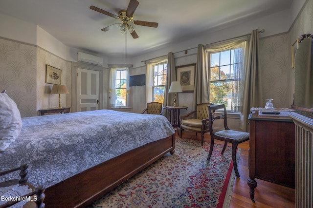 bedroom with ceiling fan, dark hardwood / wood-style flooring, and an AC wall unit