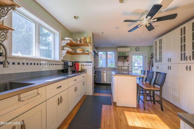 kitchen with sink, a kitchen island, a kitchen breakfast bar, tasteful backsplash, and white cabinets