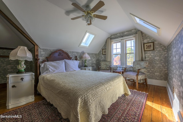 bedroom with hardwood / wood-style floors, ceiling fan, and vaulted ceiling with skylight