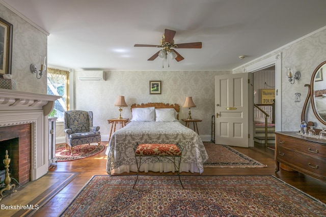 bedroom featuring a wall mounted air conditioner, crown molding, hardwood / wood-style flooring, ceiling fan, and a fireplace