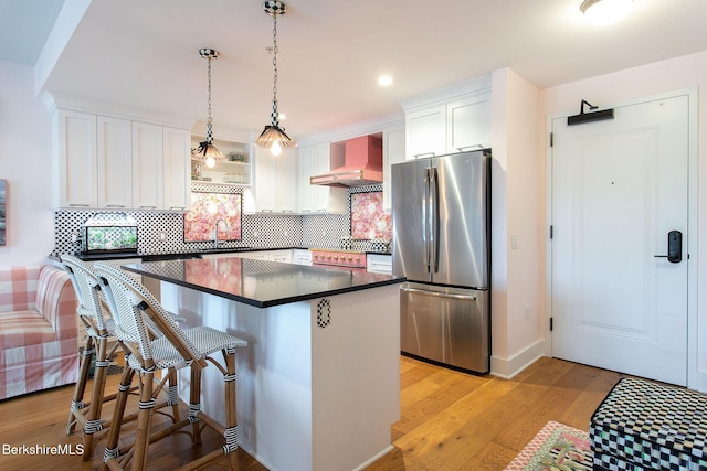 34 Bridge St, Great Barrington, MA 01230 - kitchen featuring stainless steel appliances, wall chimney range hood, dark countertops, a center island, and white cabinets