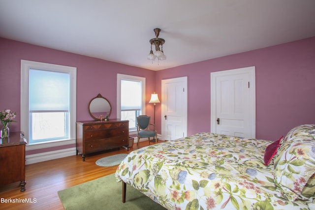 bedroom with multiple windows and hardwood / wood-style flooring