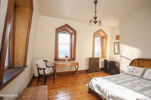 bedroom with a notable chandelier, light hardwood / wood-style floors, and radiator heating unit