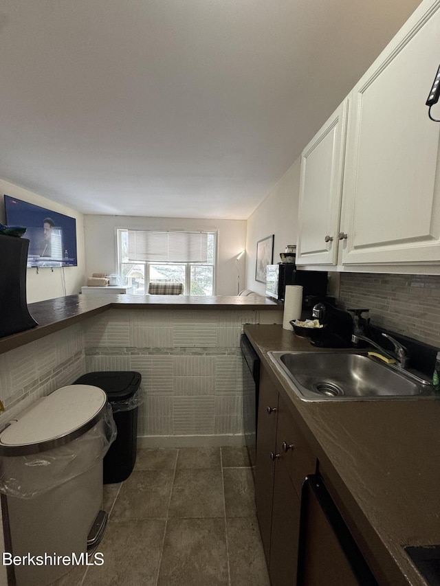 kitchen featuring dark countertops, black dishwasher, white cabinetry, and a sink