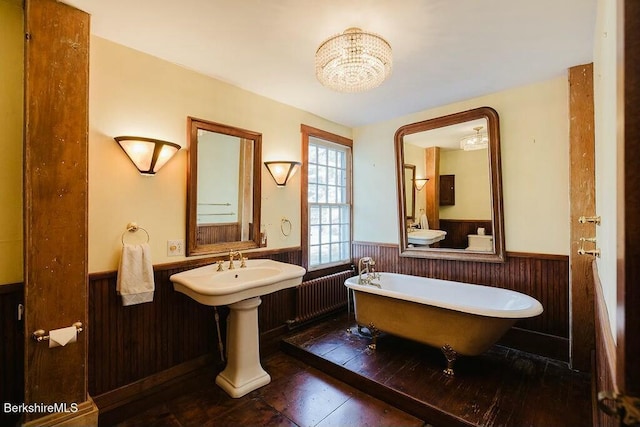 bathroom with a bathing tub, radiator heating unit, and wood walls