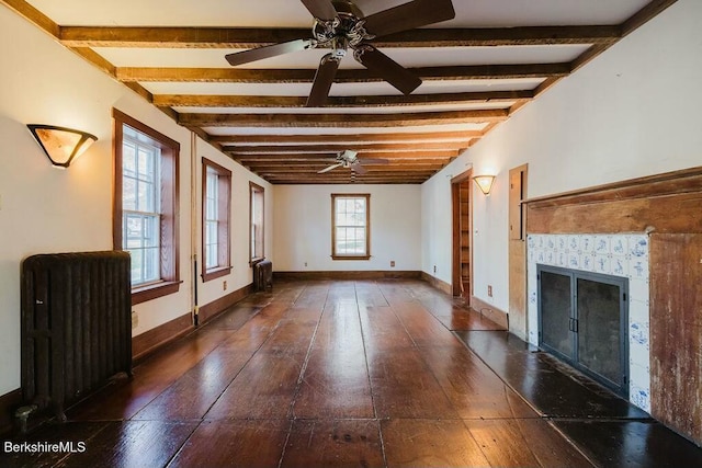 unfurnished living room with dark hardwood / wood-style floors, radiator, ceiling fan, beam ceiling, and a tiled fireplace