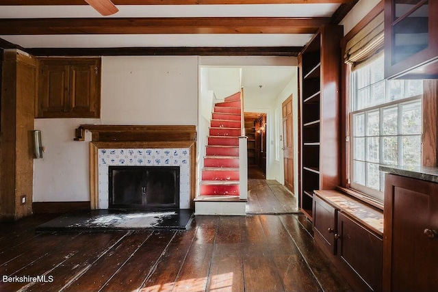 unfurnished living room featuring beamed ceiling, a fireplace, and dark hardwood / wood-style flooring