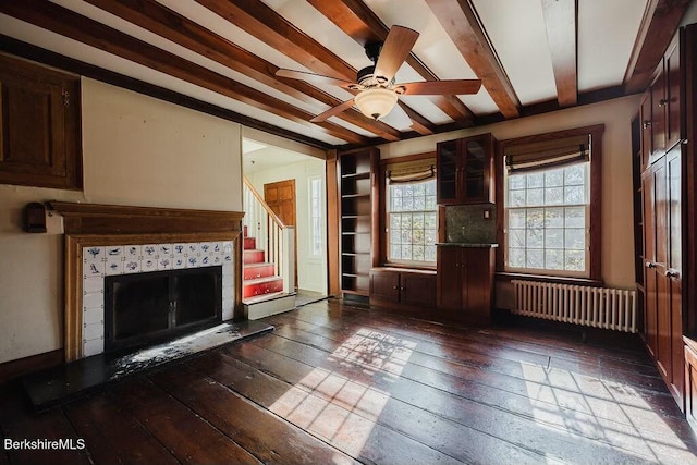 unfurnished living room featuring radiator, beam ceiling, a fireplace, and dark hardwood / wood-style floors