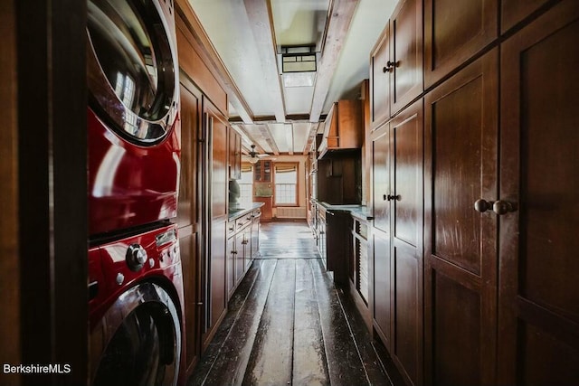 washroom featuring stacked washer / dryer, dark hardwood / wood-style floors, and cabinets