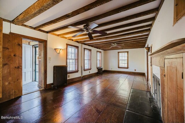 unfurnished living room featuring ceiling fan, radiator heating unit, beam ceiling, and a wealth of natural light