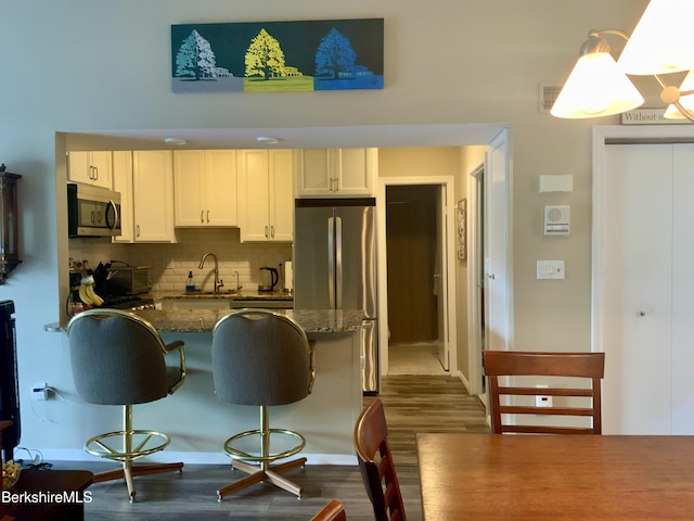 9 Rolling Hls Unit 5, Lenox, MA 01240 - kitchen with stainless steel appliances, a breakfast bar area, dark wood-type flooring, a sink, and tasteful backsplash