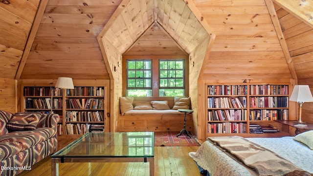 living area with hardwood / wood-style flooring, lofted ceiling with beams, wood ceiling, and wooden walls