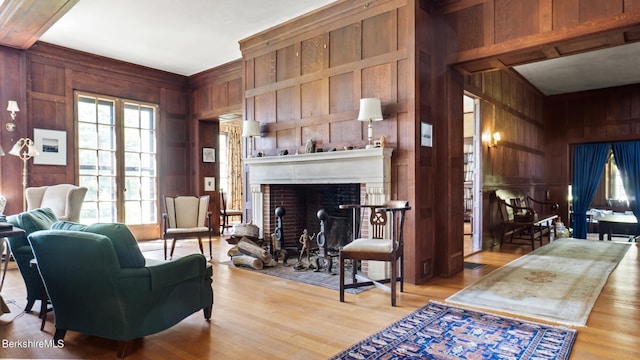 living room with wood walls, light hardwood / wood-style flooring, and a brick fireplace