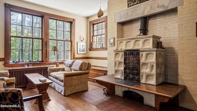 living area featuring wood-type flooring, radiator heating unit, and brick wall