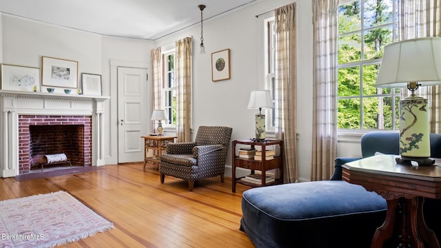 living area featuring hardwood / wood-style flooring and a brick fireplace