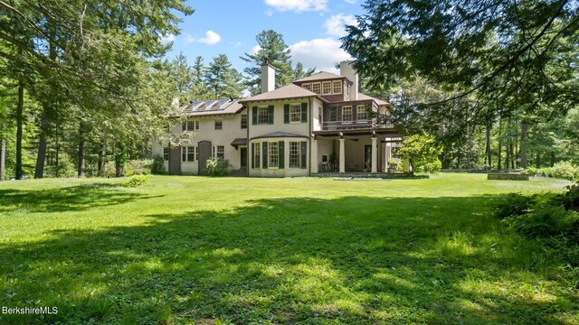 rear view of property with a wooden deck and a yard