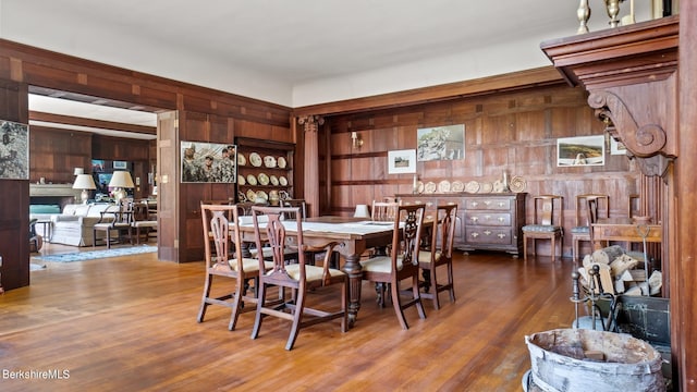 dining room with built in shelves, wood walls, and hardwood / wood-style flooring