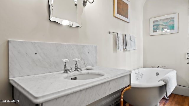 bathroom featuring vanity, hardwood / wood-style flooring, and a tub