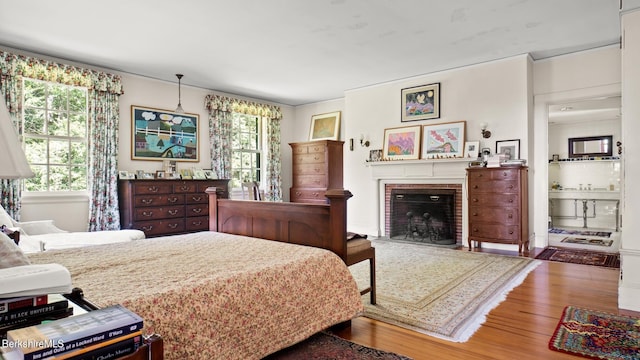 bedroom with multiple windows, a fireplace, and wood-type flooring