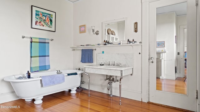 bathroom featuring backsplash, a washtub, and hardwood / wood-style flooring