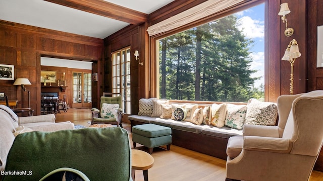 living room with beamed ceiling, light hardwood / wood-style flooring, a wealth of natural light, and wooden walls