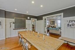 dining room featuring wainscoting, ornamental molding, wood finished floors, and a decorative wall