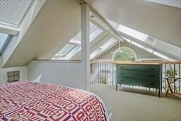 carpeted bedroom featuring vaulted ceiling and multiple windows