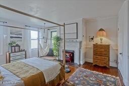 bedroom featuring ornamental molding, a fireplace, and wood finished floors