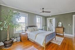 bedroom with ornamental molding, a ceiling fan, and wood finished floors