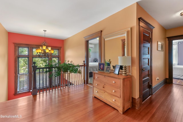 interior space featuring baseboards, hardwood / wood-style flooring, and a notable chandelier