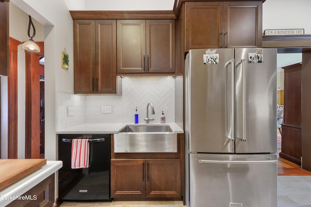 kitchen with tasteful backsplash, light countertops, a sink, black dishwasher, and high end fridge