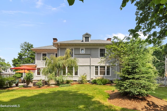 back of property featuring a lawn and a chimney