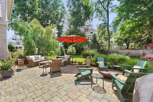 view of patio with fence and an outdoor living space with a fire pit