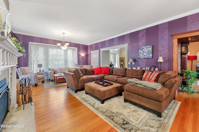 living area featuring light wood-style floors, plenty of natural light, a fireplace, and a notable chandelier