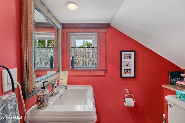 bathroom featuring a sink, vaulted ceiling, and toilet