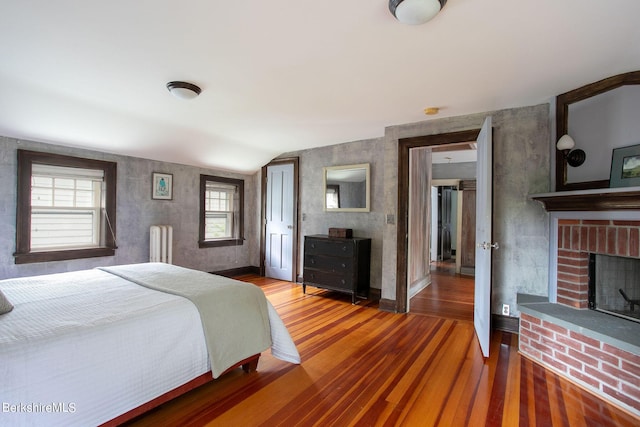 bedroom featuring multiple windows, radiator heating unit, hardwood / wood-style floors, and lofted ceiling