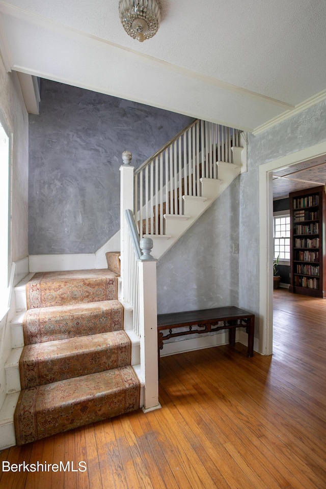 stairs featuring wood-type flooring and crown molding