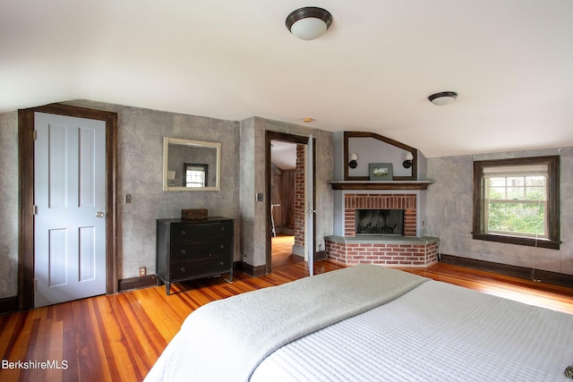 bedroom with wood-type flooring and a brick fireplace