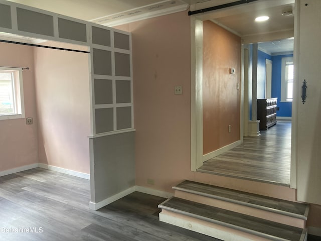 hallway featuring wood finished floors, crown molding, and baseboards