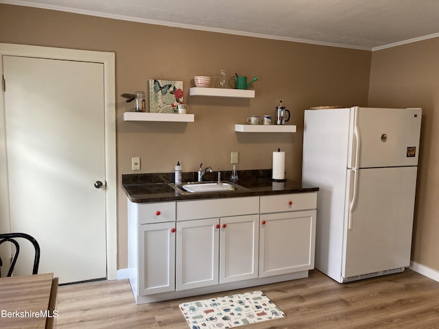 kitchen featuring freestanding refrigerator, a sink, open shelves, light wood-style floors, and crown molding