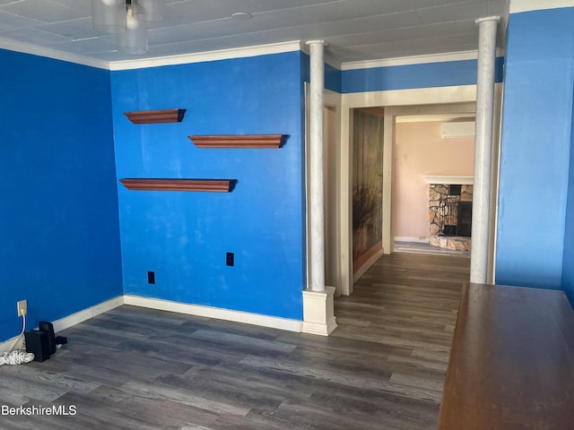 spare room with wood finished floors, crown molding, baseboards, a wall mounted AC, and a fireplace